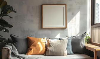 Modern living room with sunlight illuminating a blank wooden frame on a textured concrete wall above a cozy sofa photo