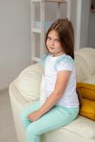 Child with a cast on a broken wrist or arm smiling and having fun on a couch. Positive attitude, recovery and kid concept. photo