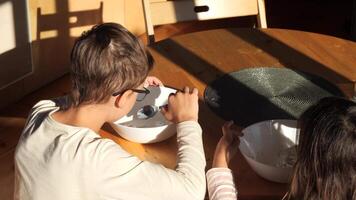 Boy eating yogurt with a spoon at the table with his sister video