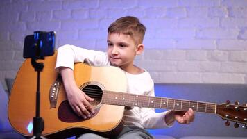 boy learns to play guitar using online courses on his phone app. e-learning video