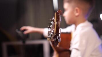 Boy holding and clicks smartphone with mobile music apps. Guitar lesson online video
