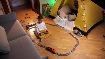 boy controls a toy train on the railway using a tablet, remote control video