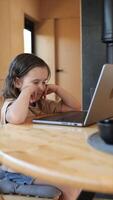 vertical girl sitting at desk is concentrating while working on laptop video
