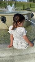 vertical Little girl watching water flowing from fountain video