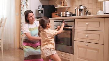 Mother teaching daughter to use oven for cooking together video