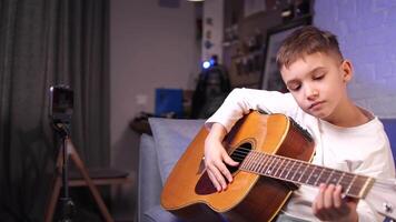 a boy learns to play the guitar using a mobile application. e-learning concept video