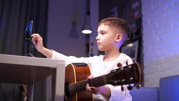 Boy holding and clicks smartphone with mobile music apps. Guitar lesson online video