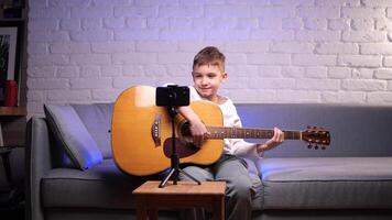 boy smiles learns to play the guitar using online courses, mobile application video