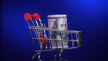 close-up of a stack of US dollar bills in a rotating shopping cart, trolley video