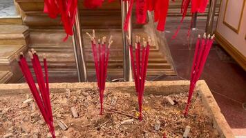Red incense sticks burning in a traditional temple setting, symbolizing spirituality, devotion, and cultural practices. Ideal for projects related to Asian culture, religious ceremonies, meditation video