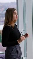 woman in eyeglasses while standing by the window Vertical video
