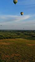 aérostats Voyage dans le air dans été. panoramique vue de la nature avec beaucoup chaud air des ballons. dirigeables en volant plus de le des champs contre le bleu ciel. aérien voir. verticale video