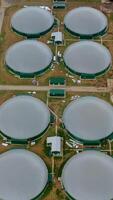 Modern biogas plant on field. Flying over the storage tanks for biomass production. Environmentally friendly biogas plant. Top view. Vertical video
