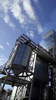 Grain elevators for drying seeds. Modern grain terminal. White smoke goes into the air from grain-drying complex. Metal tanks of elevator outdoors. Vertical video