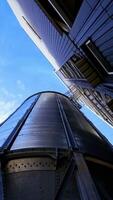 Industrial grain storage tanks. Large silver elevators for processing grain. Modern silos. Close-up. View from below. Vertical video