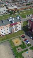 Beautiful view of newly built complex with cars in the streets and green grass near the buildings. Camera moves back. Aerial view Vertical video