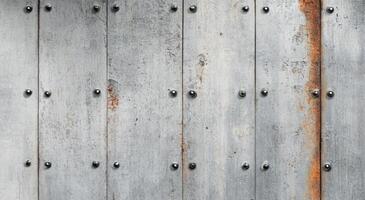 Weathered metal panels with rust and rivets on an industrial wall photo