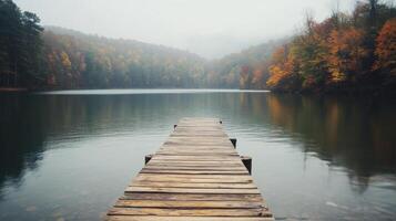 Calm autumn lake view with a wooden dock under clear blue skies photo