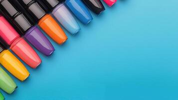 Vibrant nail polish bottles arranged on a blue surface with green leaves nearby photo