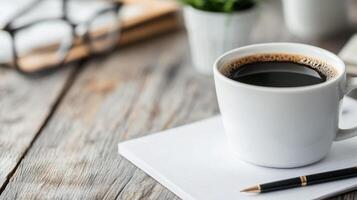 Morning coffee beside notebooks and glasses on a rustic wooden table photo