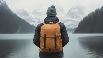 Person standing by a lake with mountains in the background on a cloudy day photo