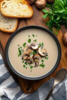Creamy mushroom soup served with sliced bread on a wooden cutting board photo