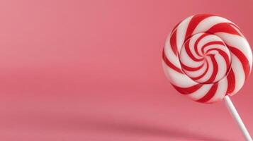 Red and white swirled lollipop against a pink background photo