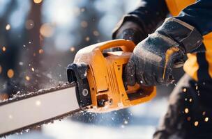 Man using chainsaw to cut tree log in winter forest with snow on the ground photo
