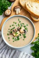Creamy mushroom soup served with sliced bread on a wooden cutting board photo