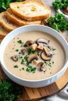 Creamy mushroom soup served with sliced bread on a wooden cutting board photo