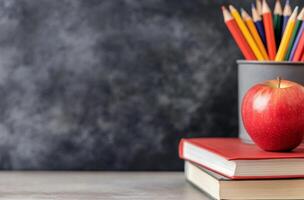 Colorful pencils and an apple on a stack of books against a blue background photo