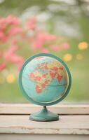 Vintage globe on wooden table with blurred flowers in the background during daytime photo