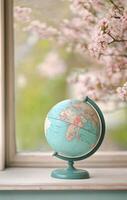 Vintage globe on wooden table with blurred flowers in the background during daytime photo
