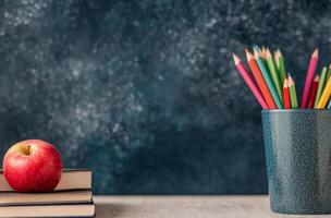 Fresh red apple sits on stacked notebooks in a classroom with colorful pencils in background photo