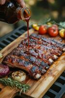 Delicious barbecue ribs being glazed with sauce on a wooden cutting board photo