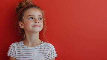 Young girl with long hair stands against a vibrant red wall during daylight photo