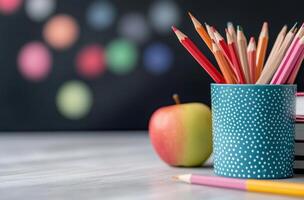 Fresh red apple sits on stacked notebooks in a classroom with colorful pencils in background photo