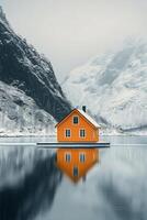 Bright orange cabin surrounded by snowy mountains and trees near frozen lake in winter photo