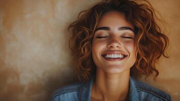 Young woman with long hair smiling warmly against a textured wall indoors in soft light photo