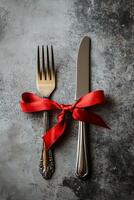 Cutlery with a red ribbon on a textured surface for a special occasion setting photo