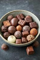 Assorted chocolates in a decorative bowl on a dark kitchen countertop photo