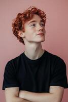 Young man with curly red hair looking up against a pink background photo
