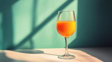 Elegant wine glass with rose-colored beverage set against a teal background photo