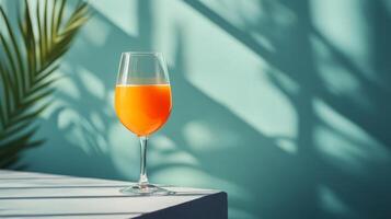 Elegant wine glass with rose-colored beverage set against a teal background photo