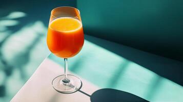 Elegant wine glass with rose-colored beverage set against a teal background photo
