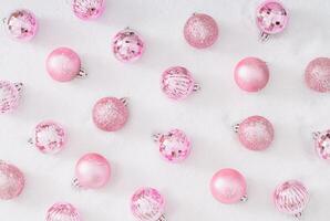 Trendy Christmas pattern made with fancy pink Christmas baubles on snowy background. Minimal creative Christmas and New Year concept. Festive winter holidays pattern backdrop. Flat lay. photo