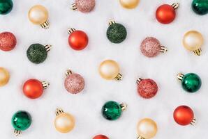 Trendy Christmas pattern composition made with colorful Xmas baubles on snowy background. Minimal Christmas and New year concept. Creative festive winter holiday pattern backdrop. Flat lay. photo
