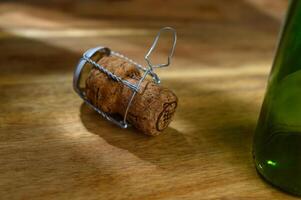 One champagne cork and part of a bottle, on a wooden table on a white background photo