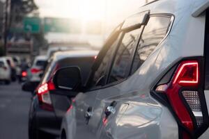 Rear side of white car on the aspahlt road. Transtport of car turn on brake light in the business time environment of moring time. Traffic congestion and queues of cars. photo