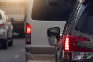 Rear side of car on the aspahlt road. Transtport of car turn on brake light in the business time environment of moring time. Traffic congestion and queues of cars. photo
